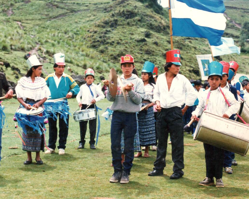 Estudiantes con banderas e instrumentos musicales durante un acto cívico.