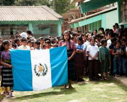 Niños de la aldea de Santiago Sacatepéquez sosteniendo la bandera de Guatemala.