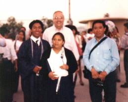 Mamá Lucía, Papá Marcos, y Marcos en su graduación de high school, junto a Sony.